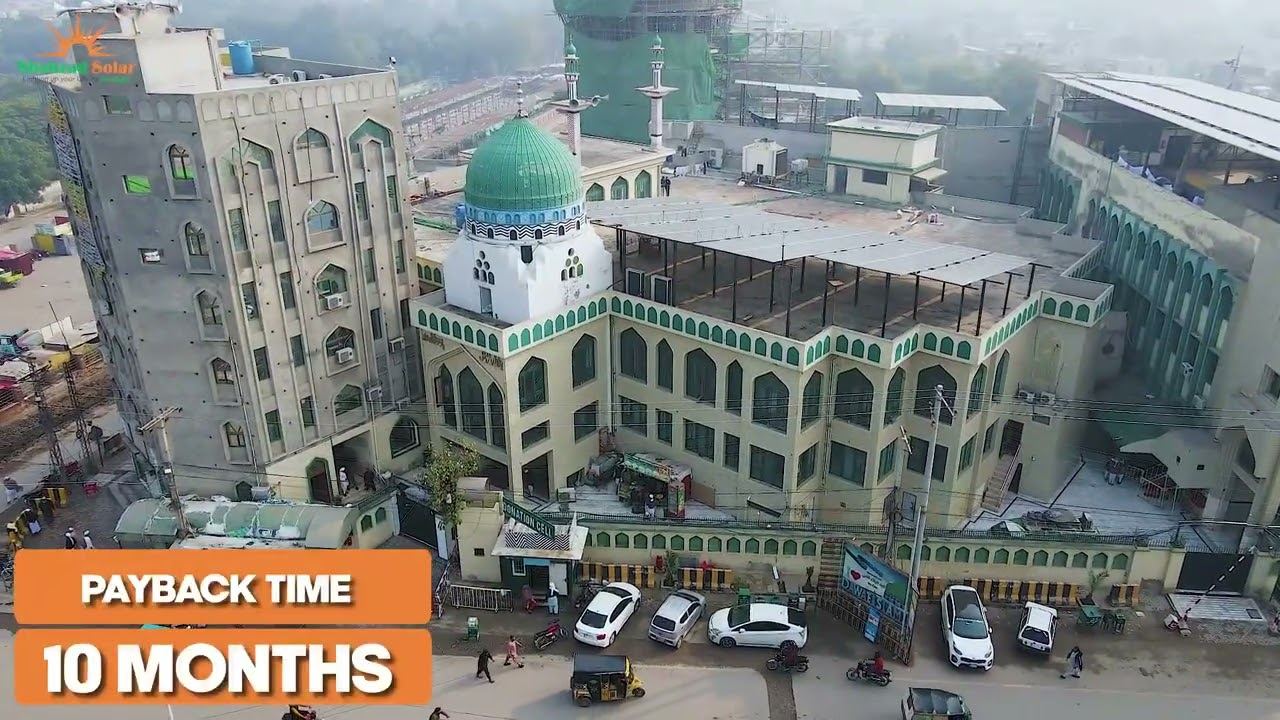 Rooftop solar array on a commercial building in Faisalabad photographed from an upper floor